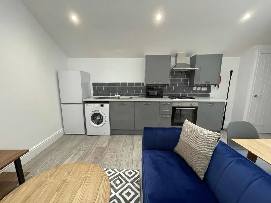 Modern kitchen with white appliances and blue sofa living area at 2 Bedroom House at 20 G, Portland Street in Lincoln Student Accommodation