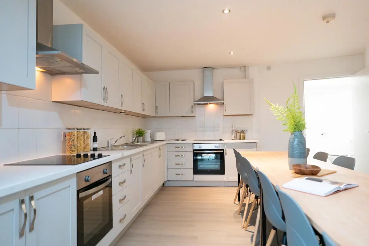 White kitchen with oven stove and dining table kitchen at 1 Bedroom House at 328, Flat 2, Claremont Road in Manchester Student Accommodation