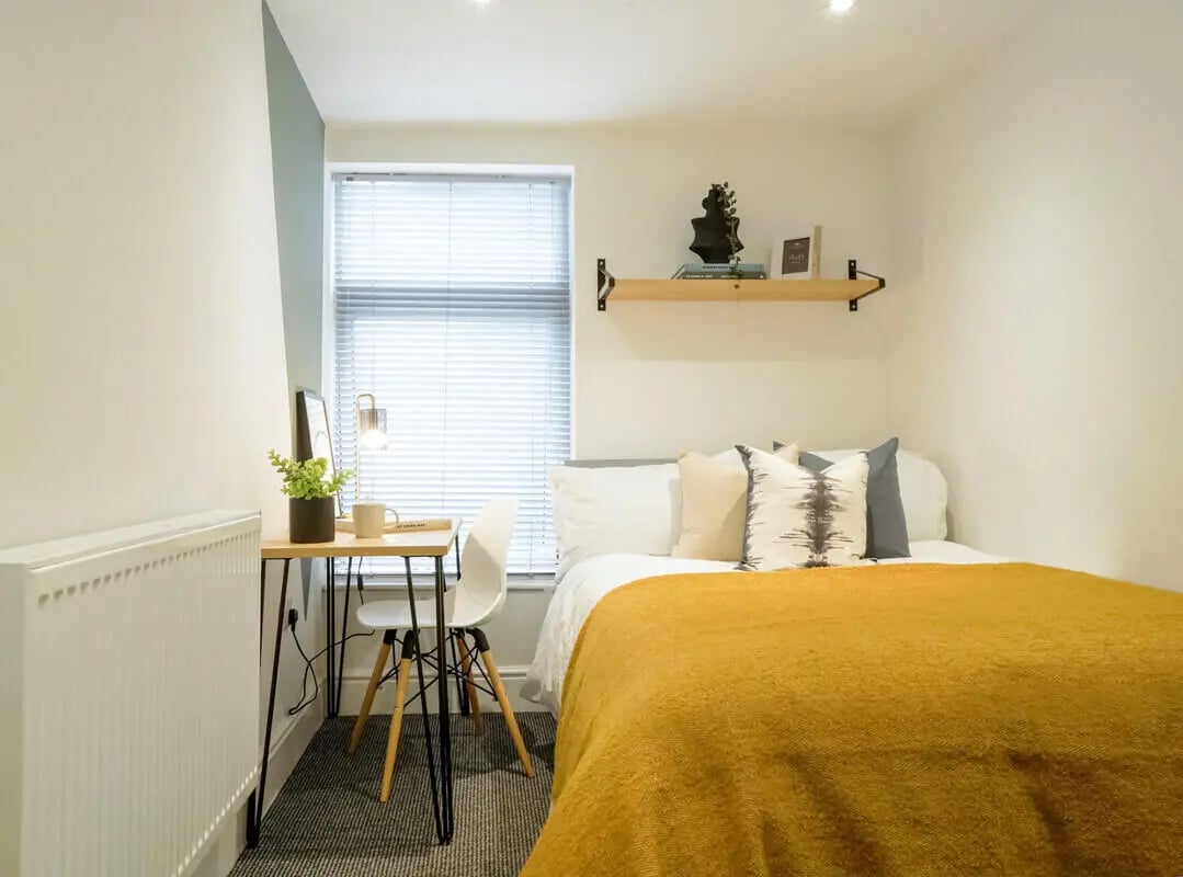 Desk bed with pillows radiator and lamp bedroom at 6 Bedroom House at 28, Ruskin Avenue in Manchester Student Accommodation