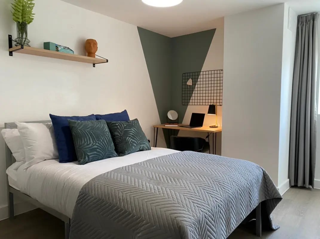 Bed with grey quilt desk with laptop and lamp bedroom at 6 Bedroom House at 232, West Parade in Lincoln Student Accommodation