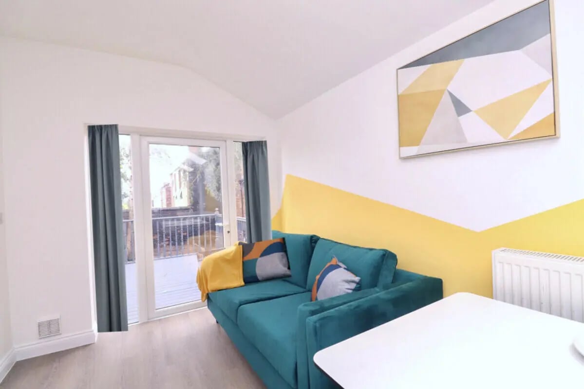 Turquoise sofa yellow blanket abstract art living room at 5 Bedroom House at 99, Monks Road in Lincoln Student Accommodation