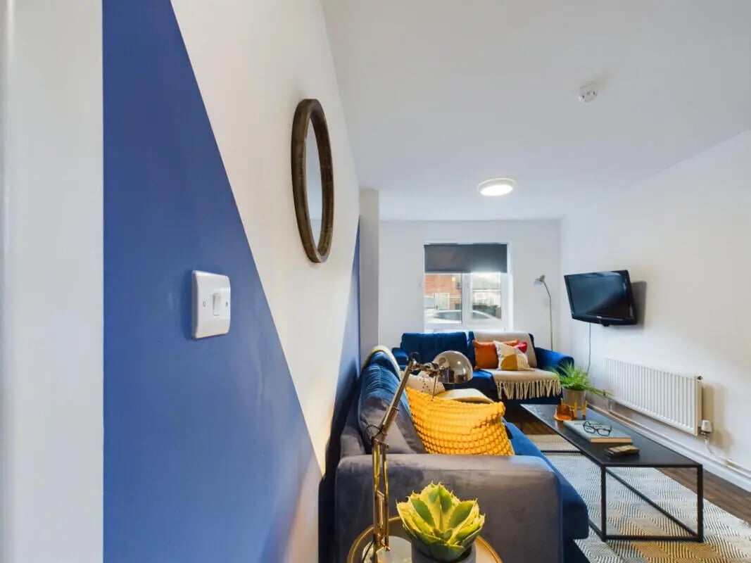 Blue sofas with yellow pillows television living room at 6 Bedroom House at 1, Brookside in Derby Student Accommodation