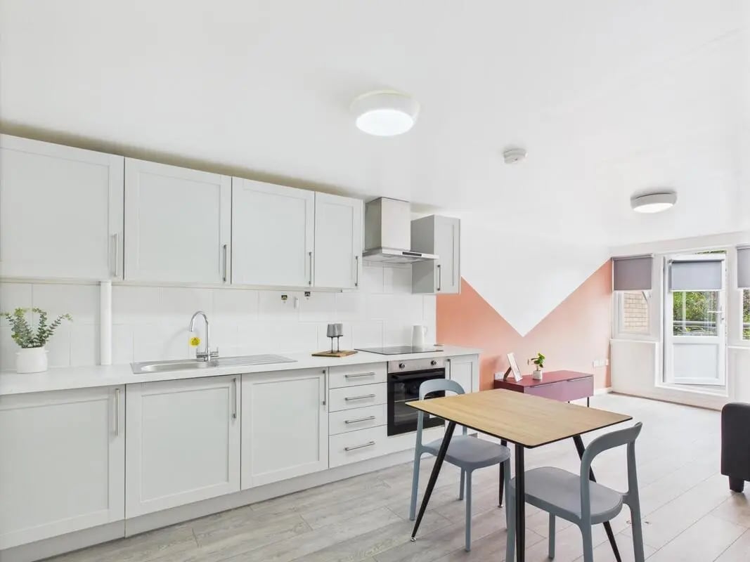White cabinets sink stove and dining table kitchen living room at 1 Bedroom House at Flat 3, Grove Street Studios, The Groves in Liverpool Student Accommodation