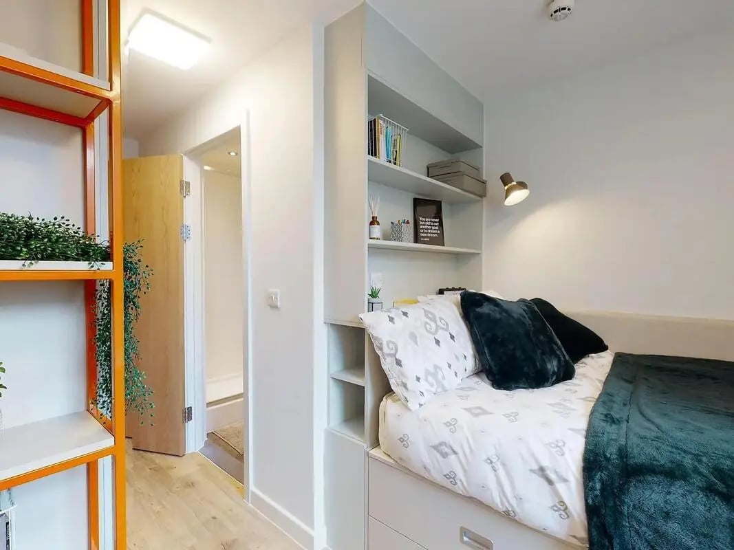 Bed with storage shelves and plants bedroom at SEREN in Swansea Student Accommodation