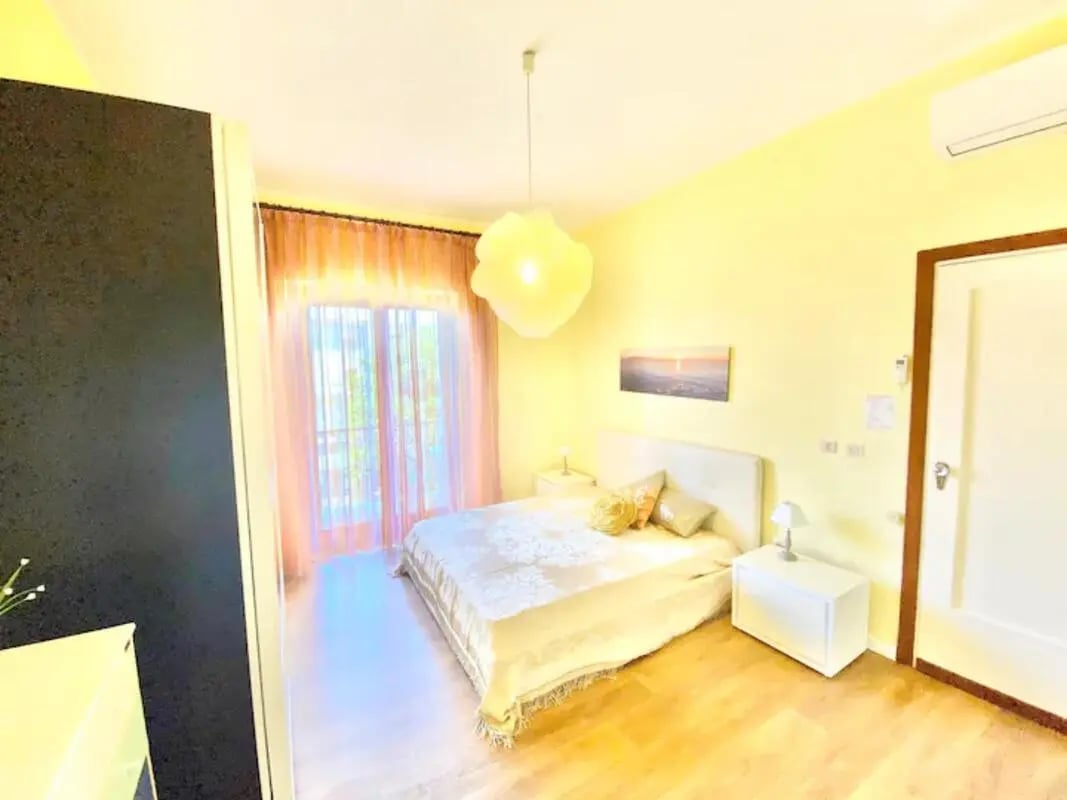 Bed nightstands lamp artwork window bedroom at Appartamento soleggiato con ampia terrazza, giardino e parcheggio in Sant'Agnello Student Accommodation