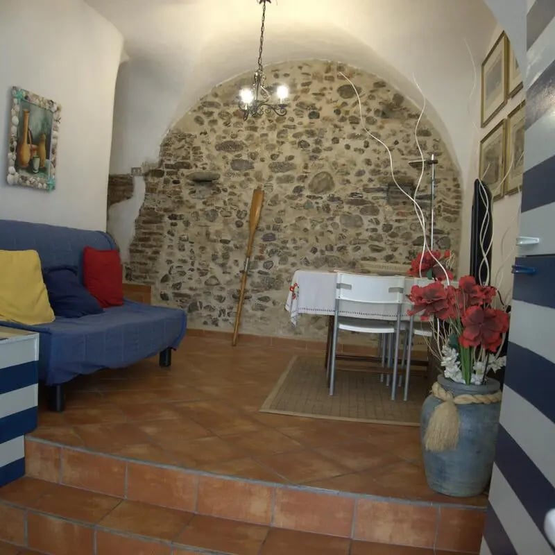 Blue sofa dining table and stone wall living area at Cosy double-bedroom apartment in Albenga (SV) in Albenga Student Accommodation