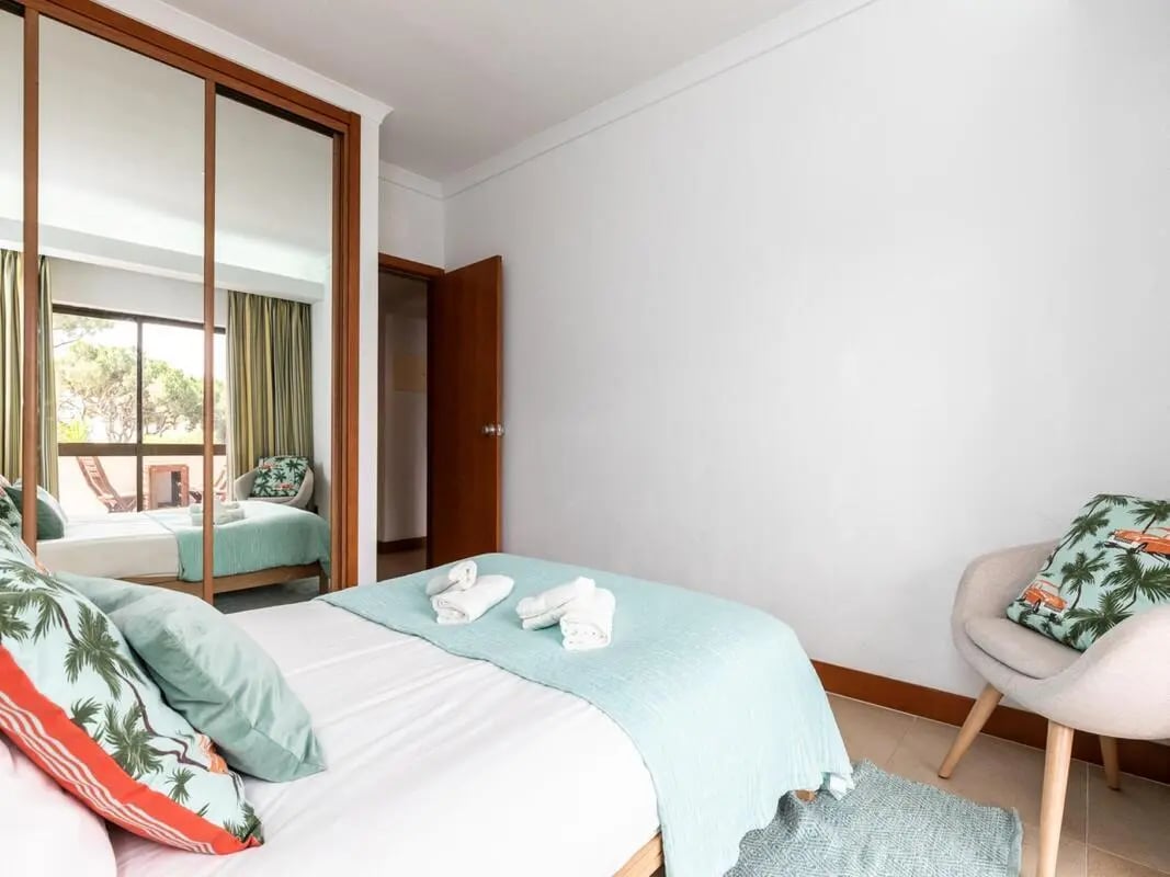 Bed with blue blanket and pillows armchair bedroom at Nice 1-bedroom flat in Faro in Faro Student Accommodation