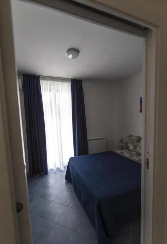 Bed dark blue curtains tile floor bedroom at Comfy Apartment close to the beach in Agrigento Student Accommodation