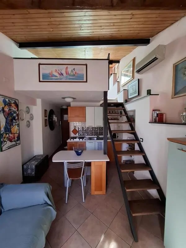 Living area with kitchen and stairs. at Apartment with Terrace in Imperia in Imperia Student Accommodation