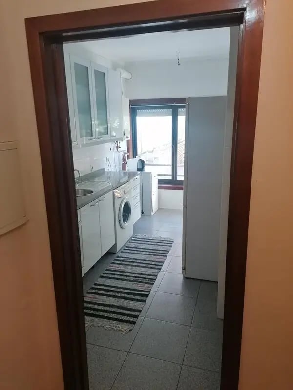 White cabinets sink washing machine rug kitchen at Cozy Single Bedroom close to Lavandeira Park in Vila Nova De Gaia Student Accommodation