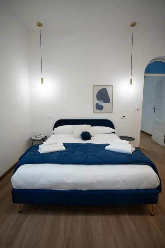 Bed with blue duvet white pillows towels bedroom at Welcoming 1-bedroom flat near Pescara Centrale in Pescara Student Accommodation