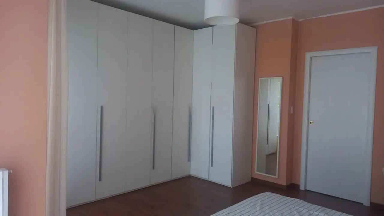 White wardrobes tall mirror white door bedroom at Comfy 3 bedroom apartment close to University of Parma in Parma Student Accommodation
