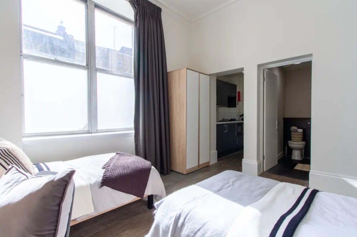 Two beds wardrobe and bathroom bedroom at Bloomsbury Janet Poole House in London Student Accommodation