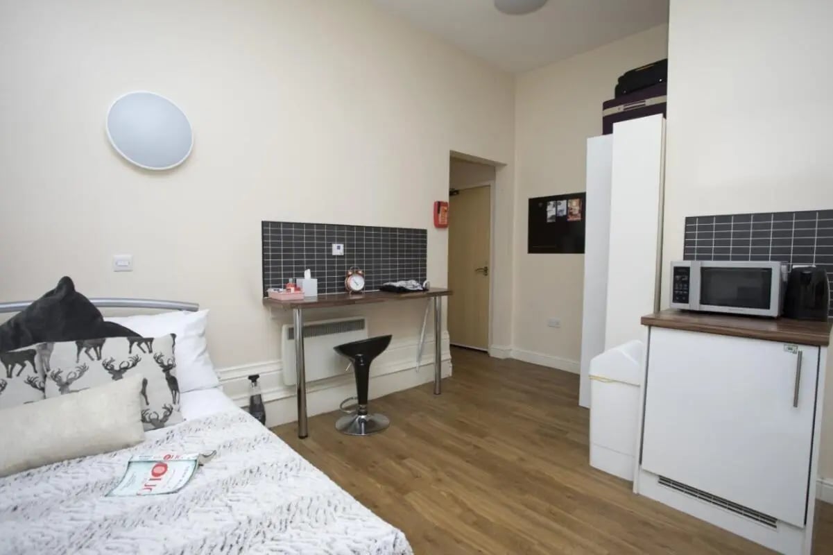 Bed desk microwave with kitchen area and study. at Daisybank Villas in Manchester Student Accommodation