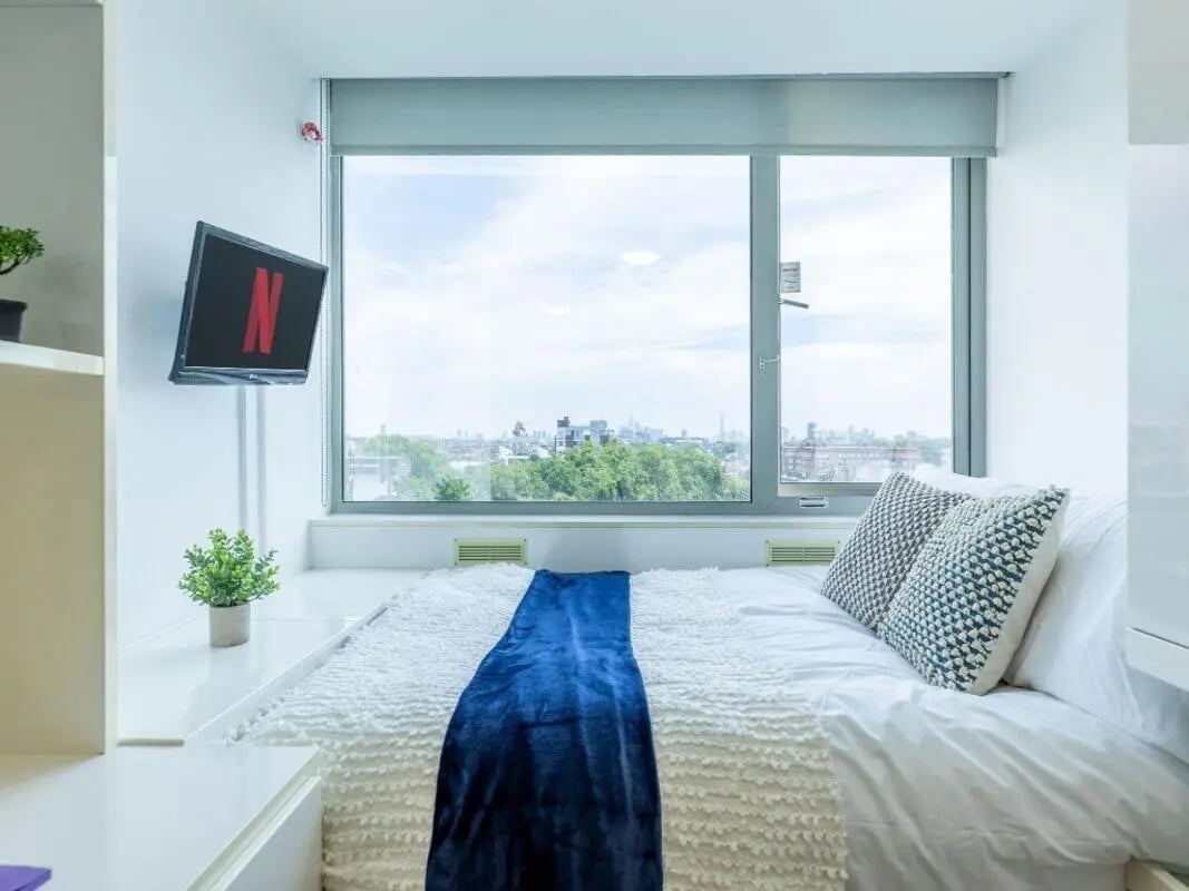 Bed with blue blanket pillows and Netflix TV bedroom at Chelsea Lightfoot Hall in London Student Accommodation