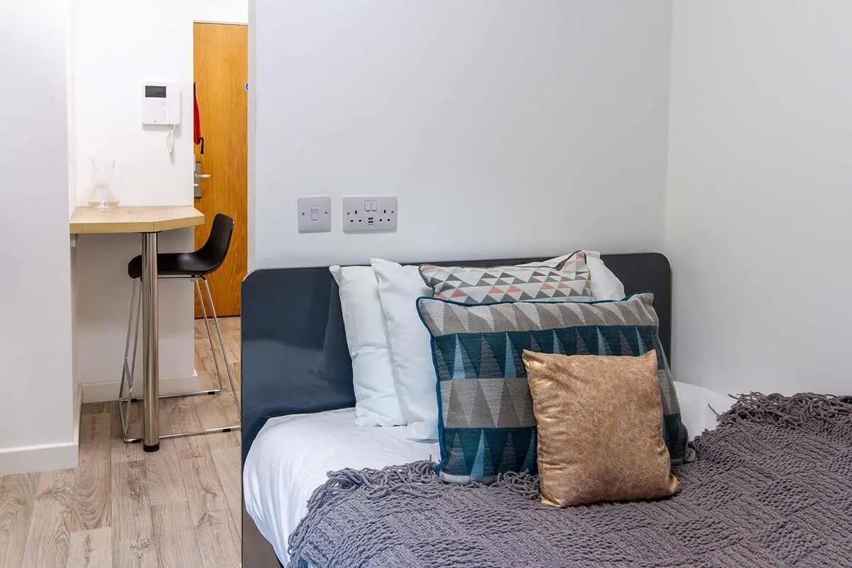 Bed with patterned pillows and desk with chair bedroom at Goods Corner in Edinburgh Student Accommodation