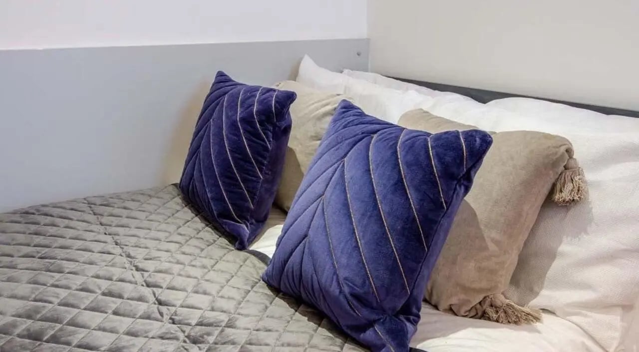 Bed with blue and beige pillows and grey bedding bedroom at Orbital in Nottingham Student Accommodation