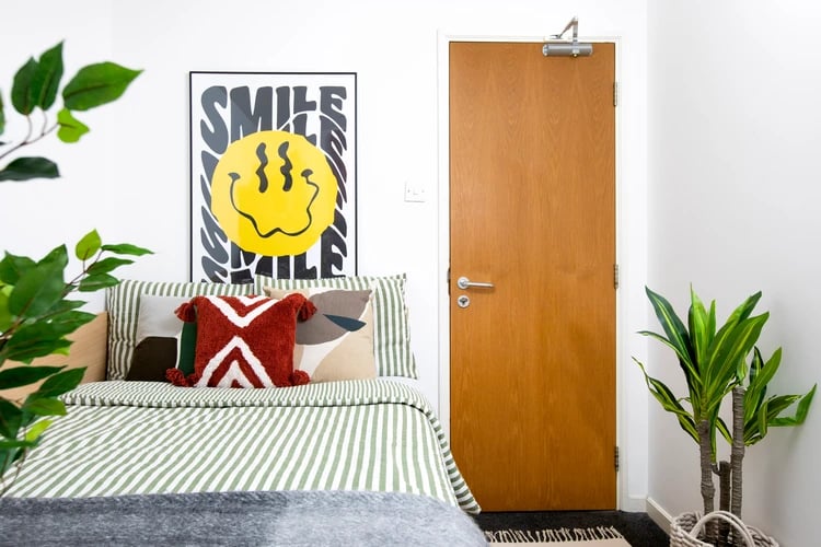 Bed with green stripes and smiley poster bedroom at Romano Court in London Student Accommodation