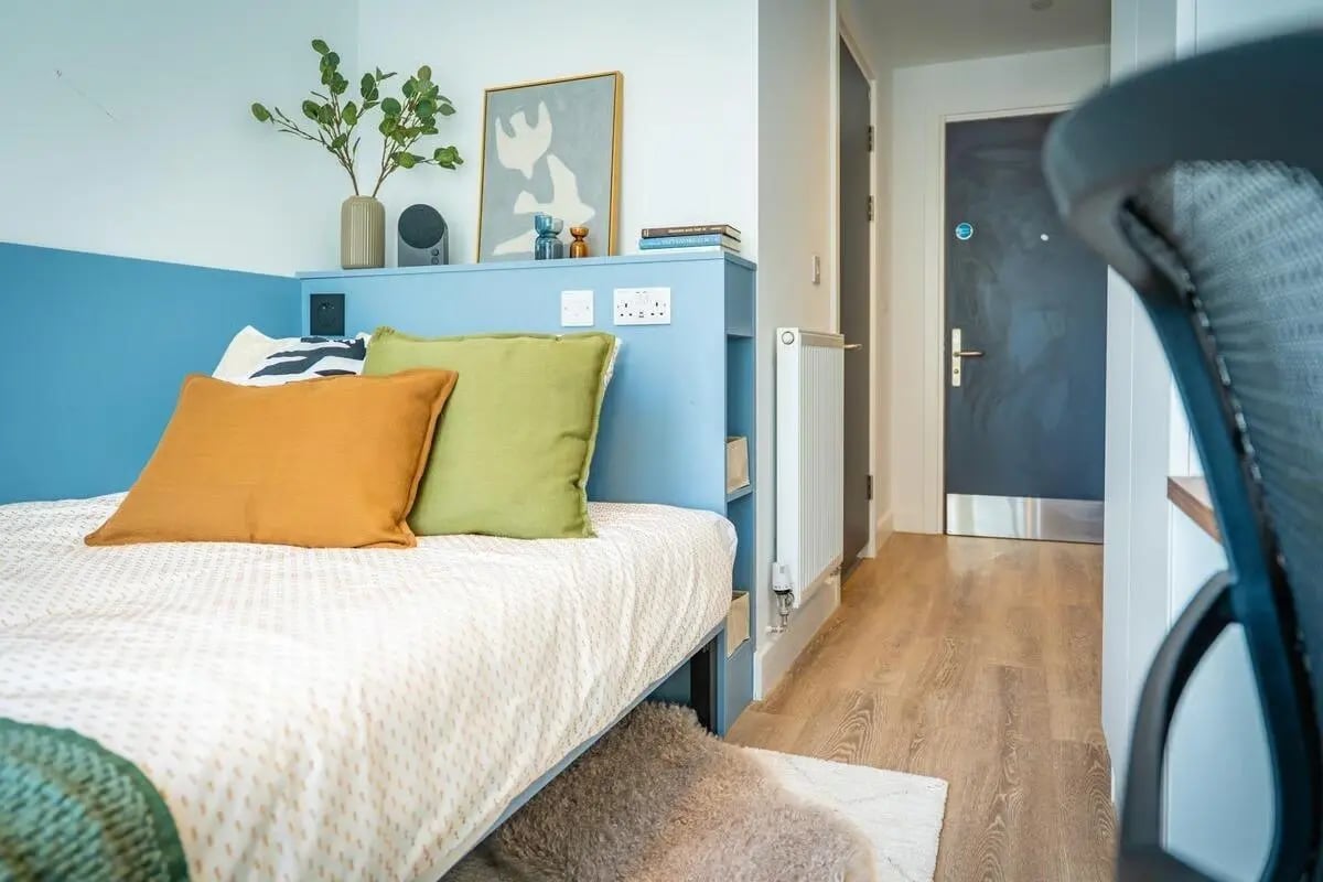 Bed with cushions plant and artwork bedroom interior at The Propeller Quarter in Bristol Student Accommodation