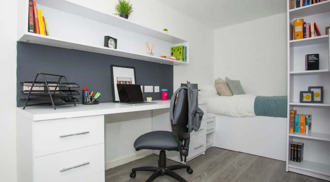 Desk with laptop bed and bookshelves bedroom at The Cube Ealing in London Student Accommodation