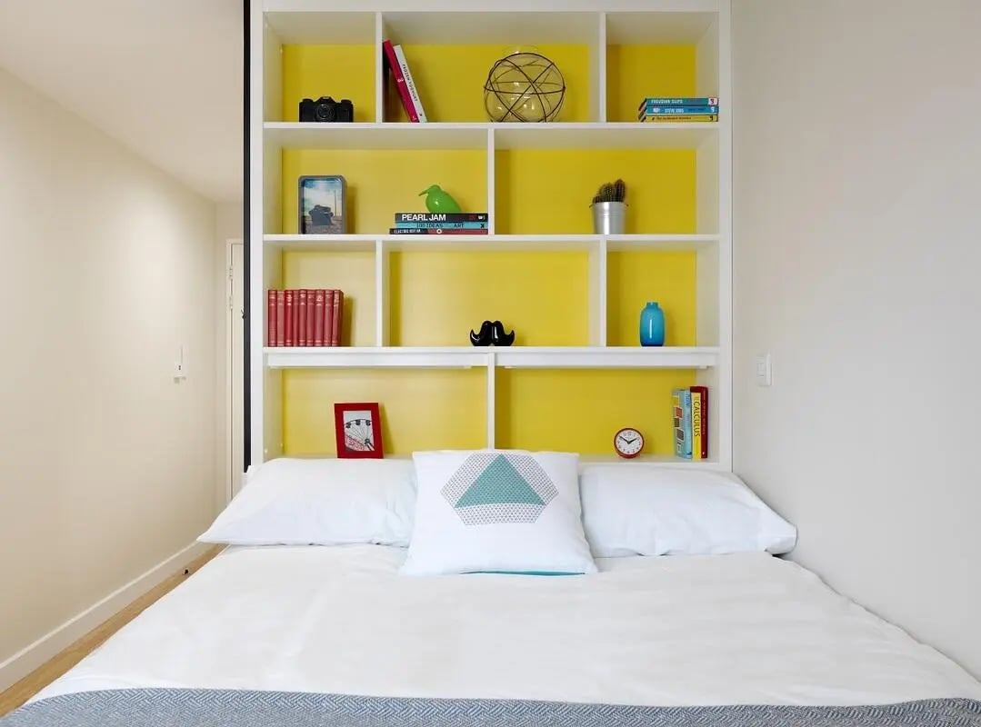 Bed with shelves containing books camera and decor bedroom at Student Castle York in York Student Accommodation