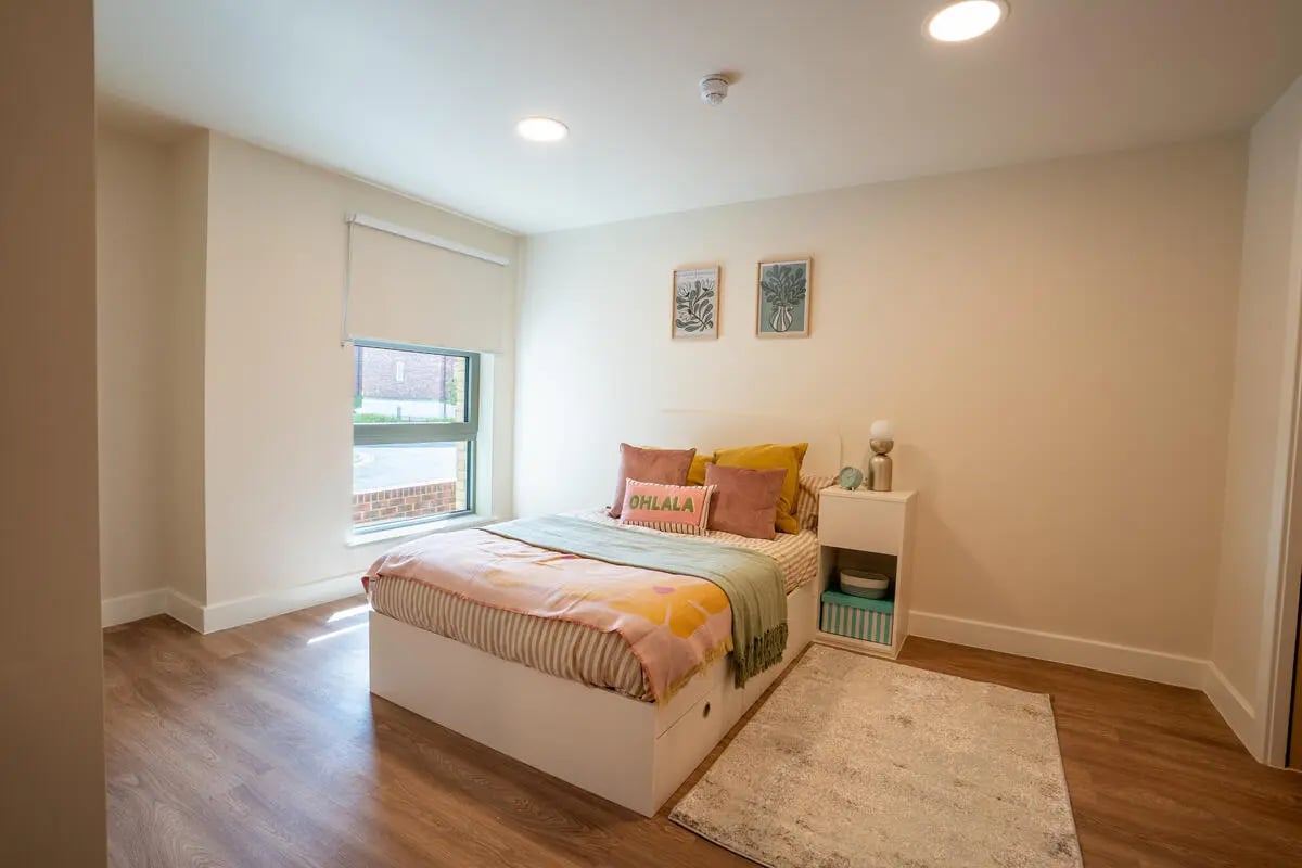 Bed with colorful pillows bedside table rug bedroom at Valerian in York Student Accommodation