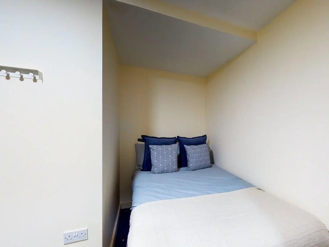 Bed with blue pillows and white blanket bedroom at The Cube in Bolton Student Accommodation