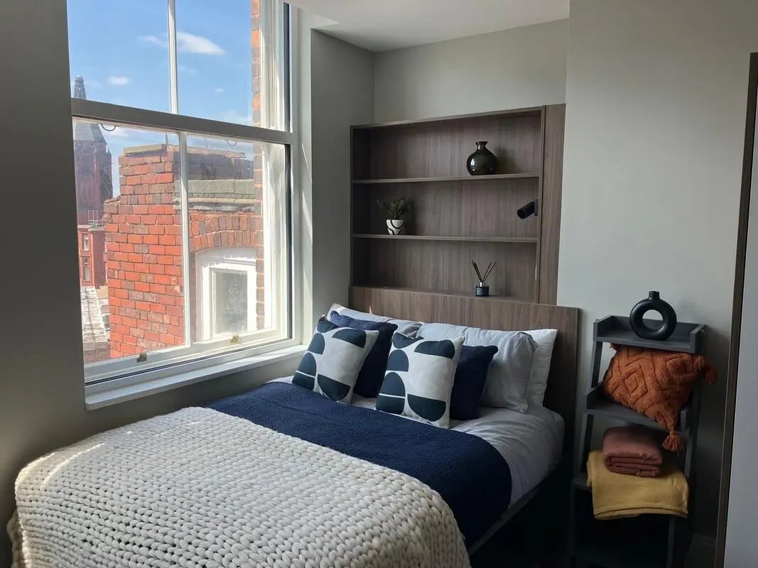 Bed with decorative pillows and shelves bedroom at Chamberlain Place in Birmingham Student Accommodation