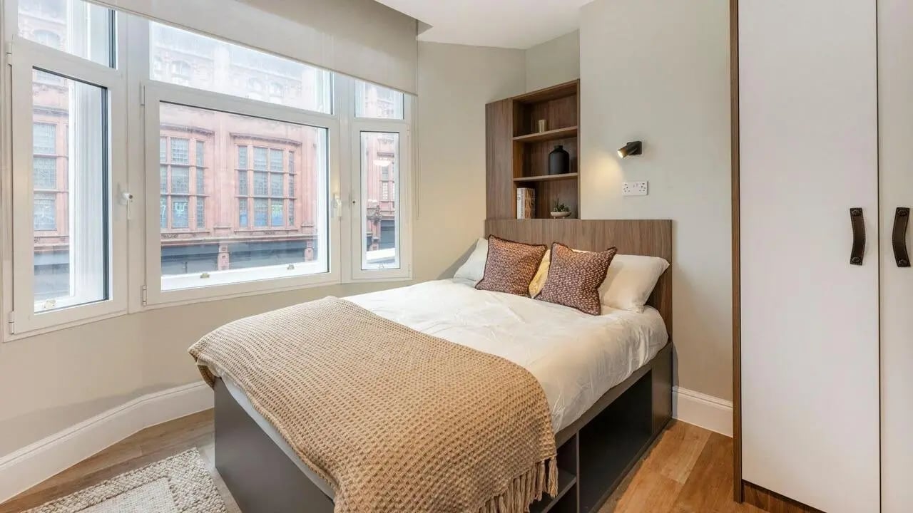 Bed with pillows throw bookshelf and wardrobe bedroom at Chamberlain Place in Birmingham Student Accommodation