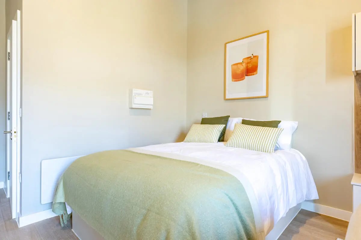 Bed with green blanket artwork and door bedroom at Fitz and Knox in Cardiff Student Accommodation