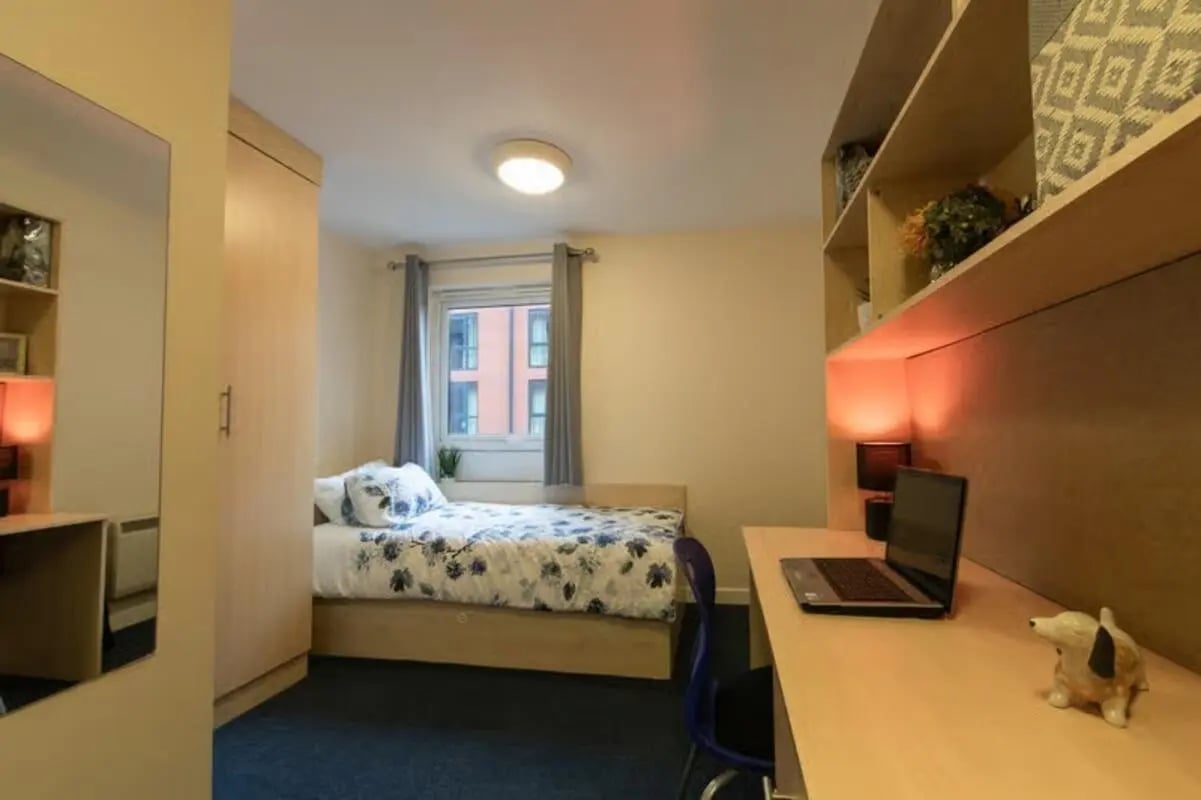 Bed with floral duvet desk with laptop bedroom. at Brayford Quay in Lincoln Student Accommodation