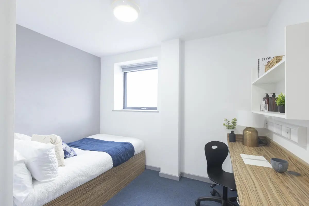 Bed with blue blanket and desk with chair bedroom at Turner Court in Newcastle Upon Tyne Student Accommodation