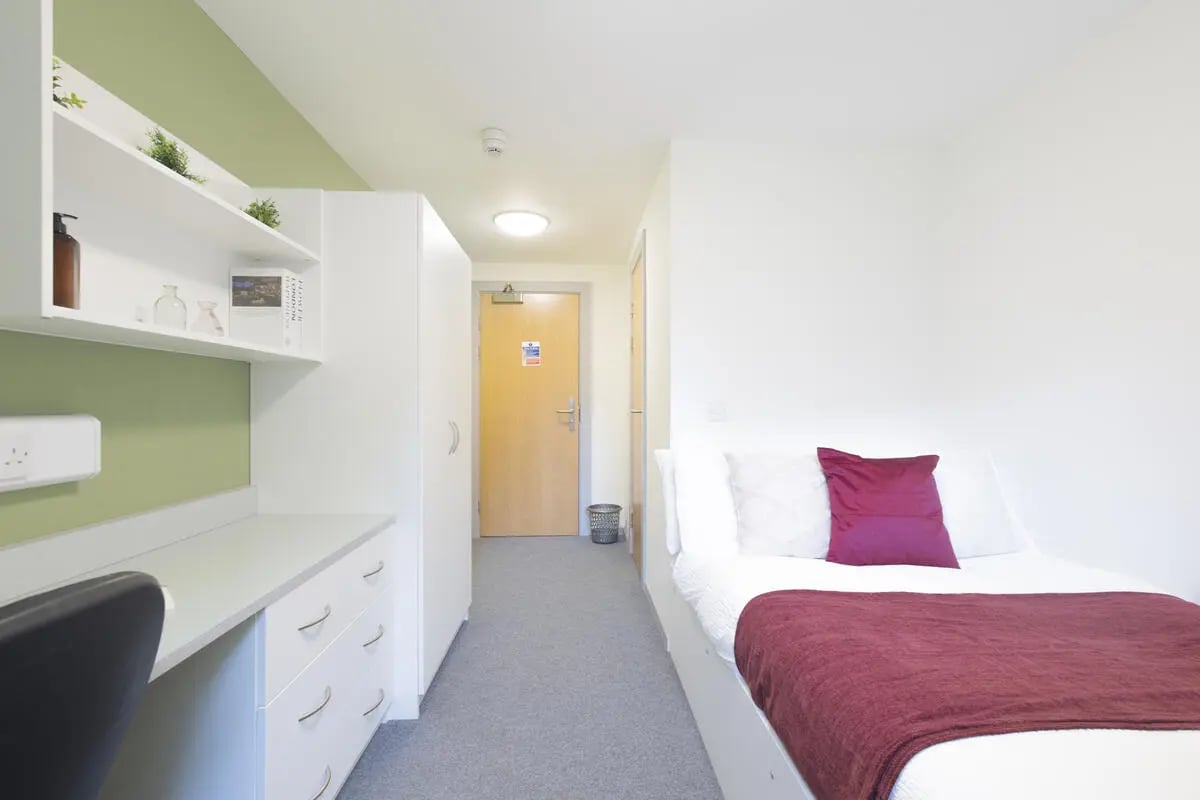 Bed with burgundy throw white bedding desk and shelves bedroom at Marshall Court in Newcastle Upon Tyne Student Accommodation
