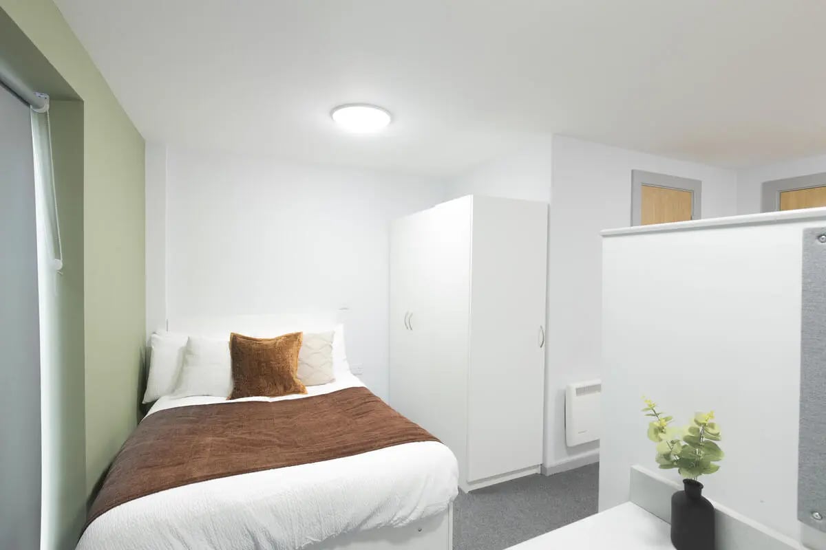 Bed with brown throw white bedding two closets and heater bedroom at Marshall Court in Newcastle Upon Tyne Student Accommodation