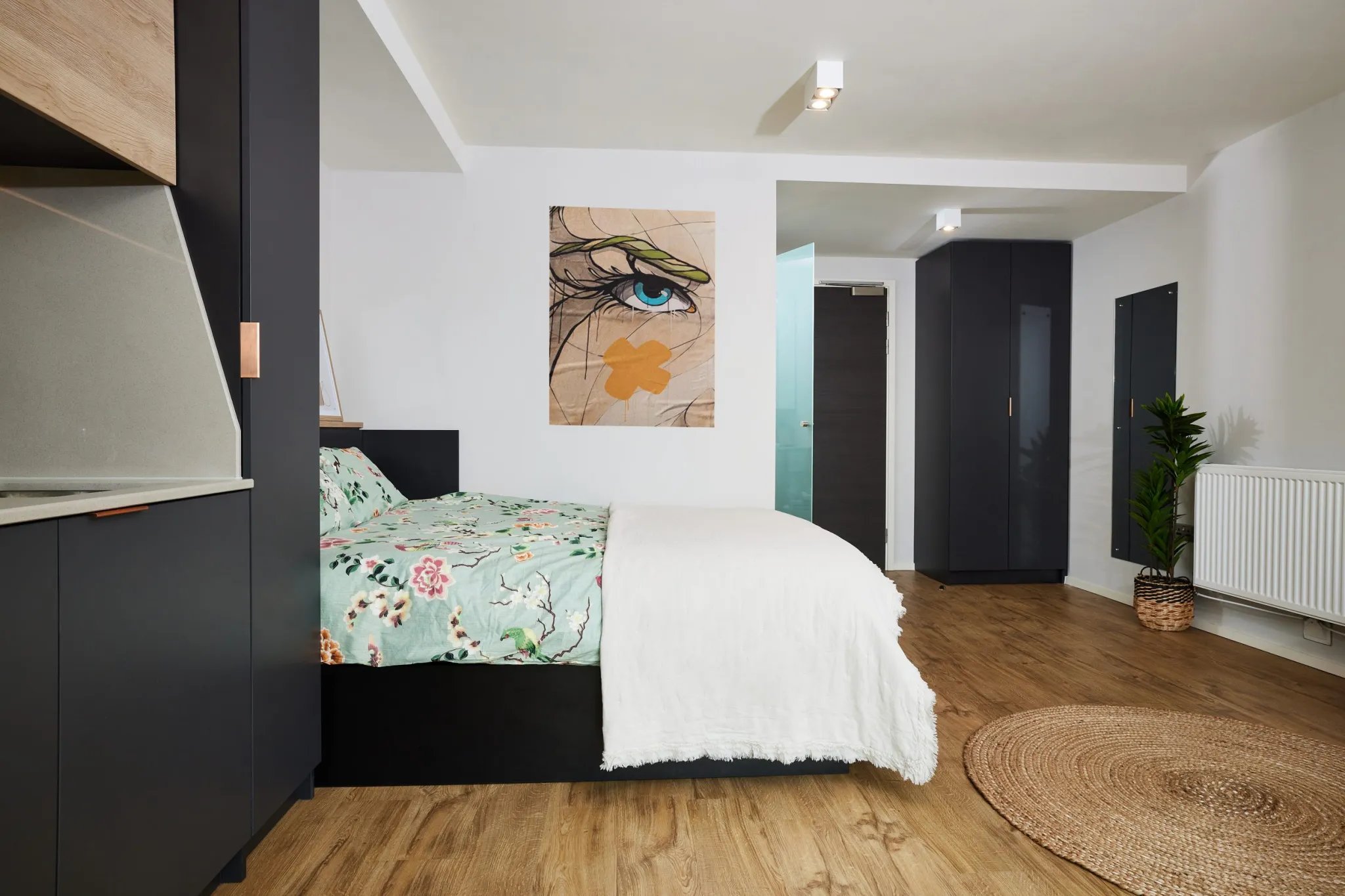 Bed with floral bedding and modern kitchen area studio at Vita Student Pebble Mill in Birmingham Student Accommodation