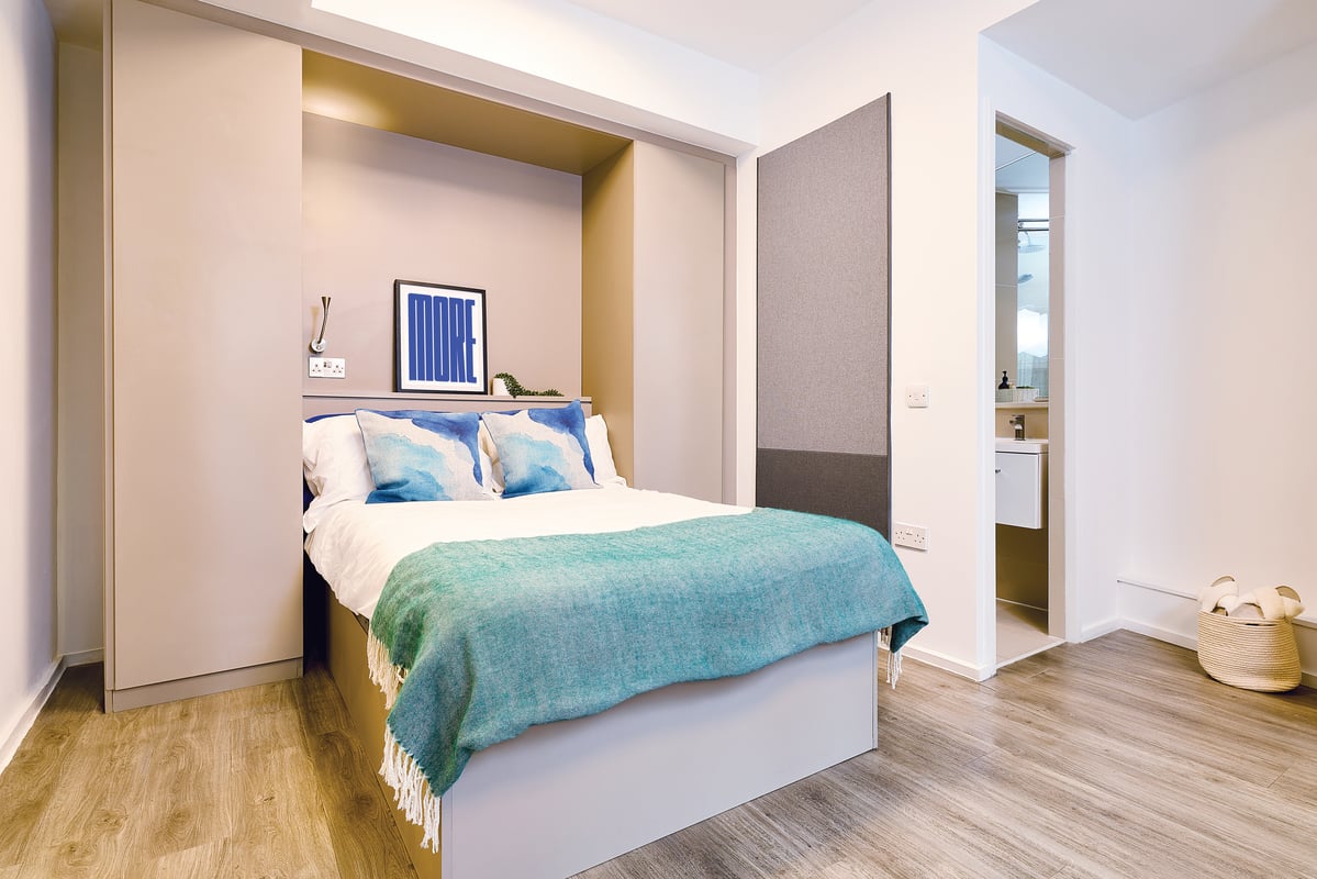 Bed with blue pillows and green blanket bedroom at Vita Student Zed Alley in Bristol Student Accommodation