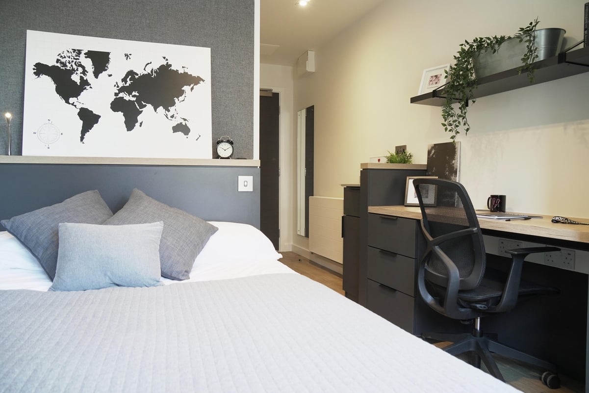 World map above bed desk and chair bedroom at Vita Student Lewisham Exchange in London Student Accommodation