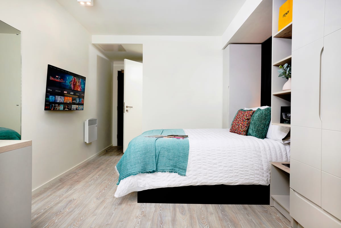 Bed with turquoise throw pillows and TV bedroom at Vita Student Leazes Park in Newcastle Upon Tyne Student Accommodation