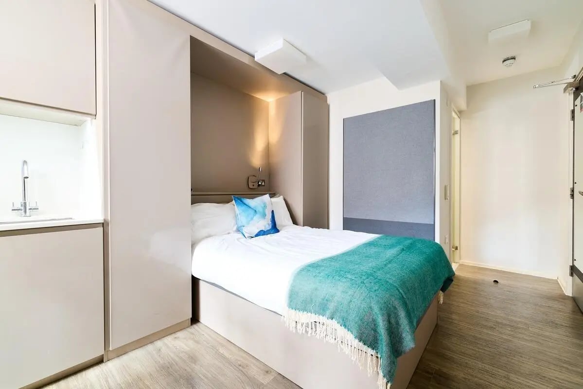 Bed with teal throw and sink area bedroom at Vita Student Portland House - Exeter in Exeter Student Accommodation