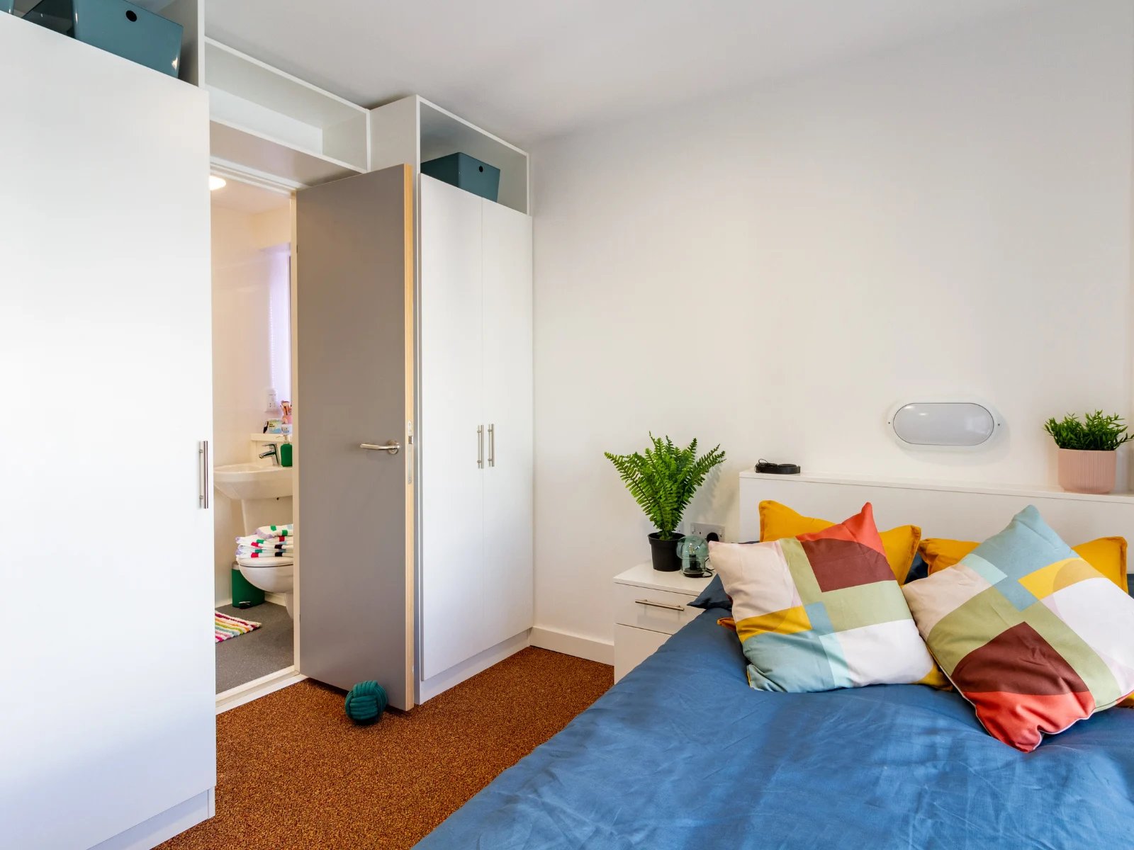 Bed toilet sink closets and colorful pillows bedroom at The Shield in Newcastle Upon Tyne Student Accommodation