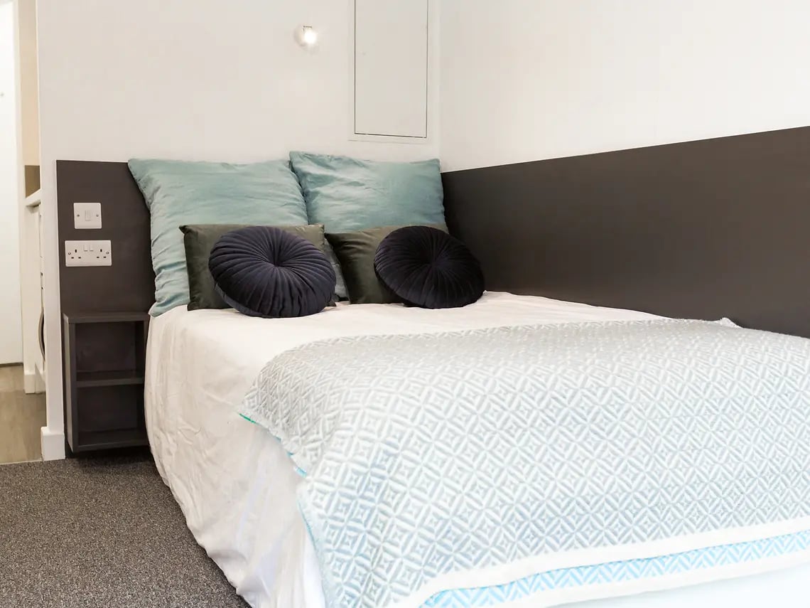 Bed with teal and navy pillows patterned throw bedroom at Canterbury Student Manor in Canterbury Student Accommodation