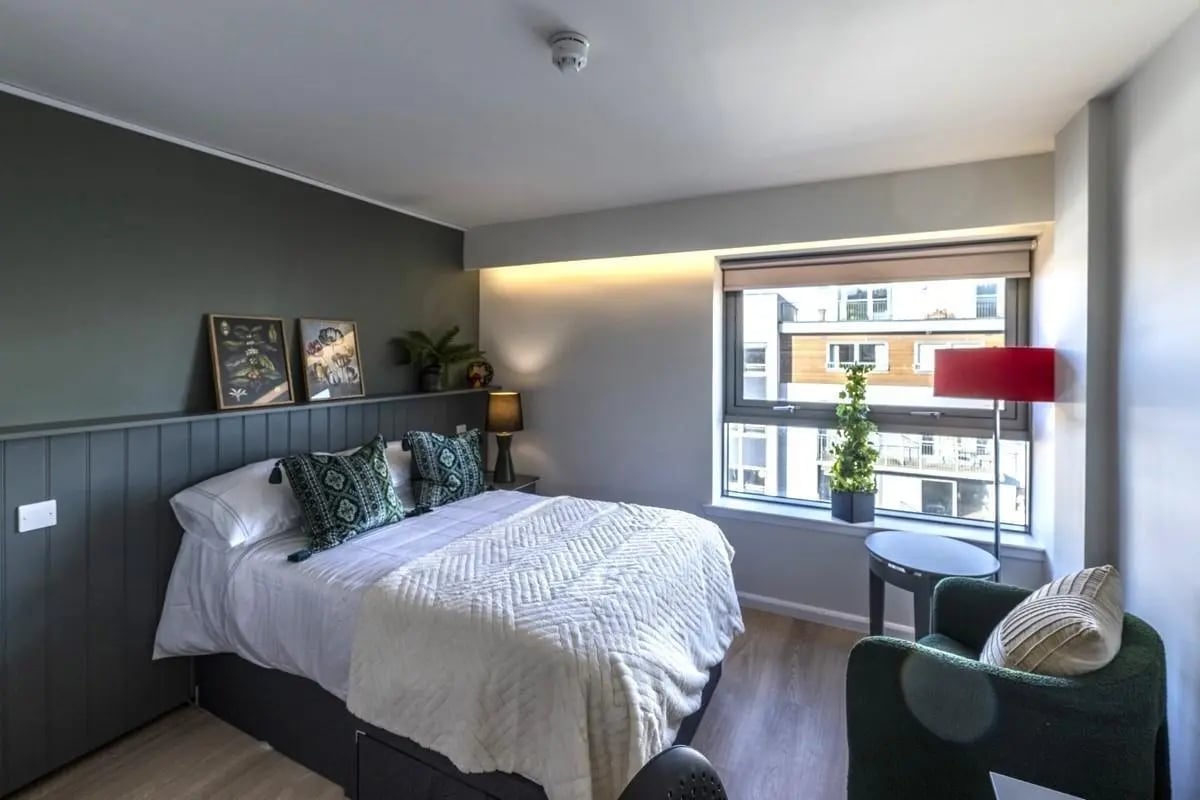 Bed with pillows artwork lamp chair and window bedroom at St. Andrew Street in Aberdeen Student Accommodation