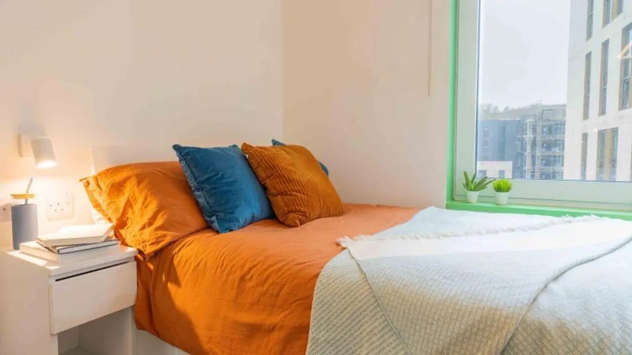 Bed with orange duvet blue orange pillows bedside table bedroom at iQ Brighton in Brighton Student Accommodation