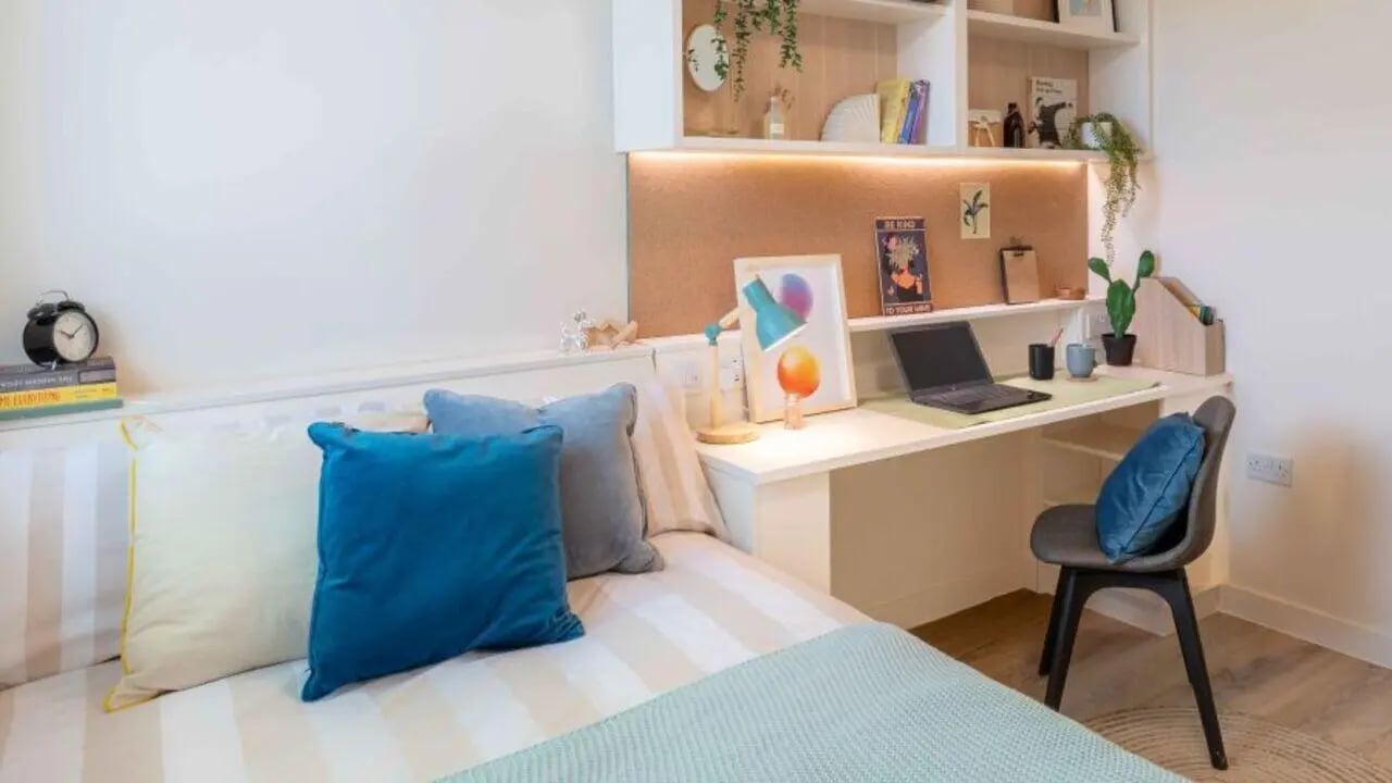 Bed pillows desk laptop chair and shelves bedroom at iQ Haywood House in London Student Accommodation