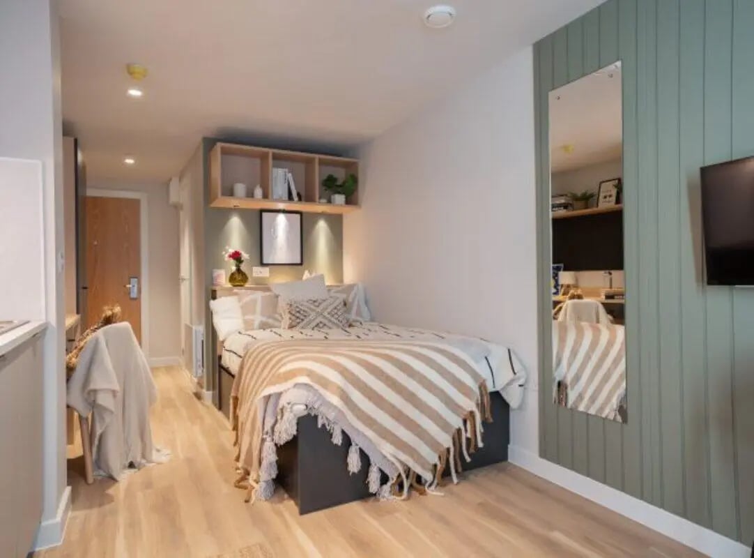 Bed with striped throw shelves mirror bedroom at Fusion Leeds in Leeds Student Accommodation