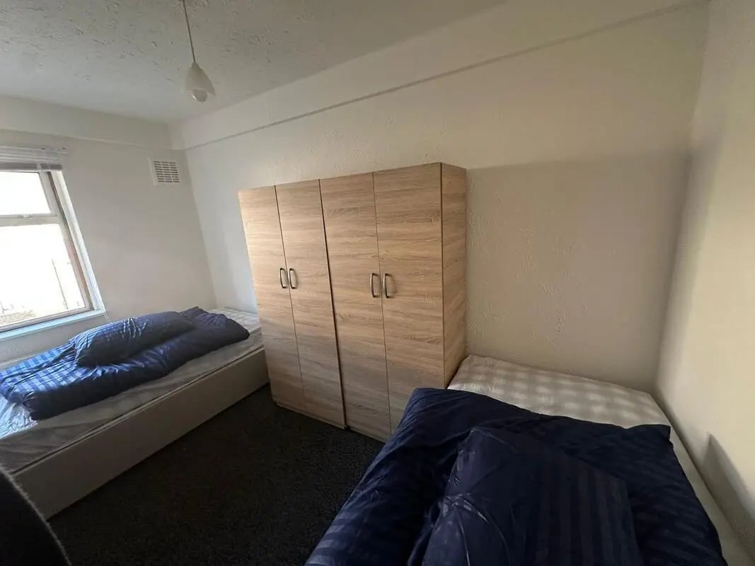 Two beds wardrobes and a window bedroom at E16 3LL, MacGregor Rd, London in London Student Accommodation