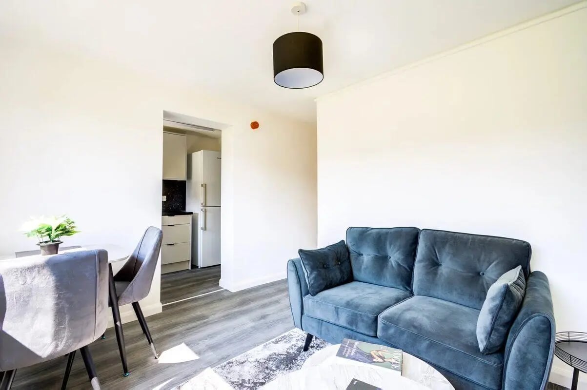 Blue sofa and dining table with kitchen living area at Clanny House in Sunderland Student Accommodation