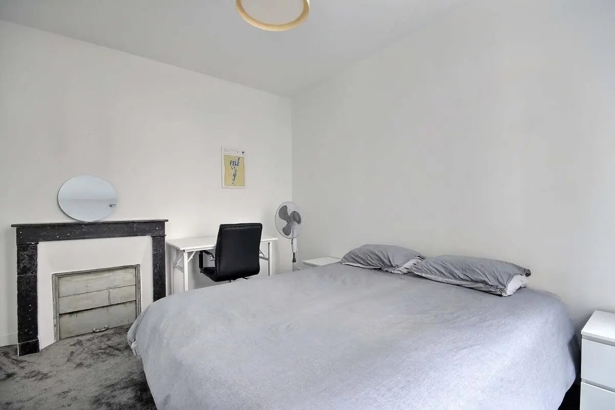 Bed desk chair fireplace round mirror bedroom at Apartment in Rue Keller, 75011 Paris, France in Paris Student Accommodation