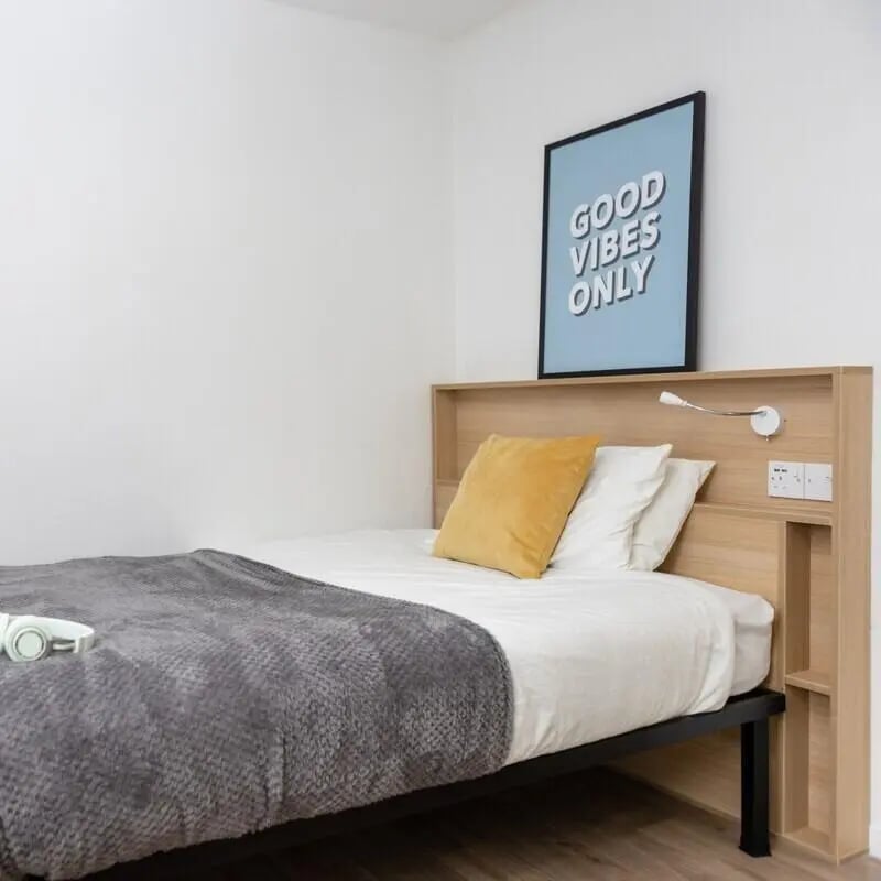 Bed with grey blanket yellow pillow framed art bedroom at Lyme Regis House in Bournemouth Student Accommodation