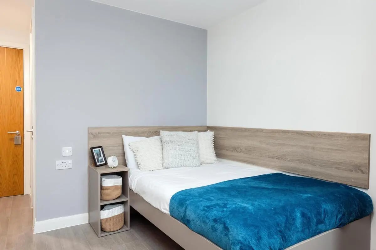 Bed with blue blanket and white pillows bedside table bedroom at Skyline in Bournemouth Student Accommodation